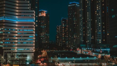 都市夜景中两名穿风衣的角色在雨巷对峙，霓虹灯光在湿地面反射，氛围紧张冷冽